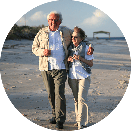 Two older adults walking along the beach